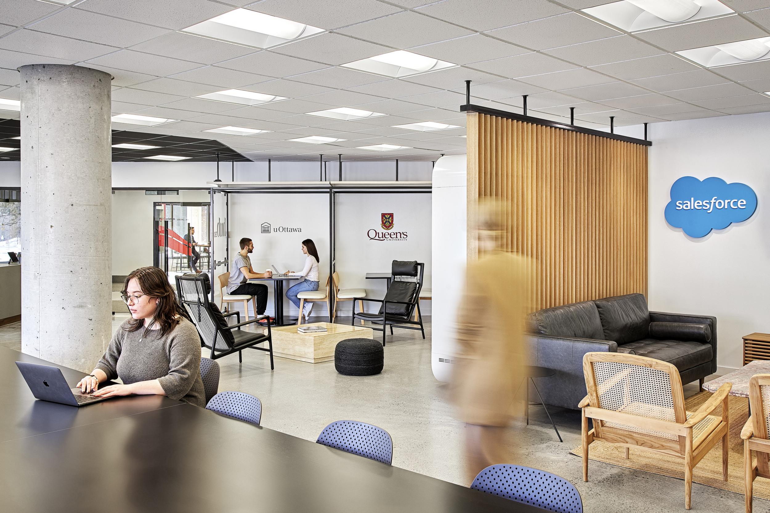 Within Hub350, people are working in different sections of a room. The sections belong to different organizations of which salesforce, Queens university and University of Ottawa are shown.