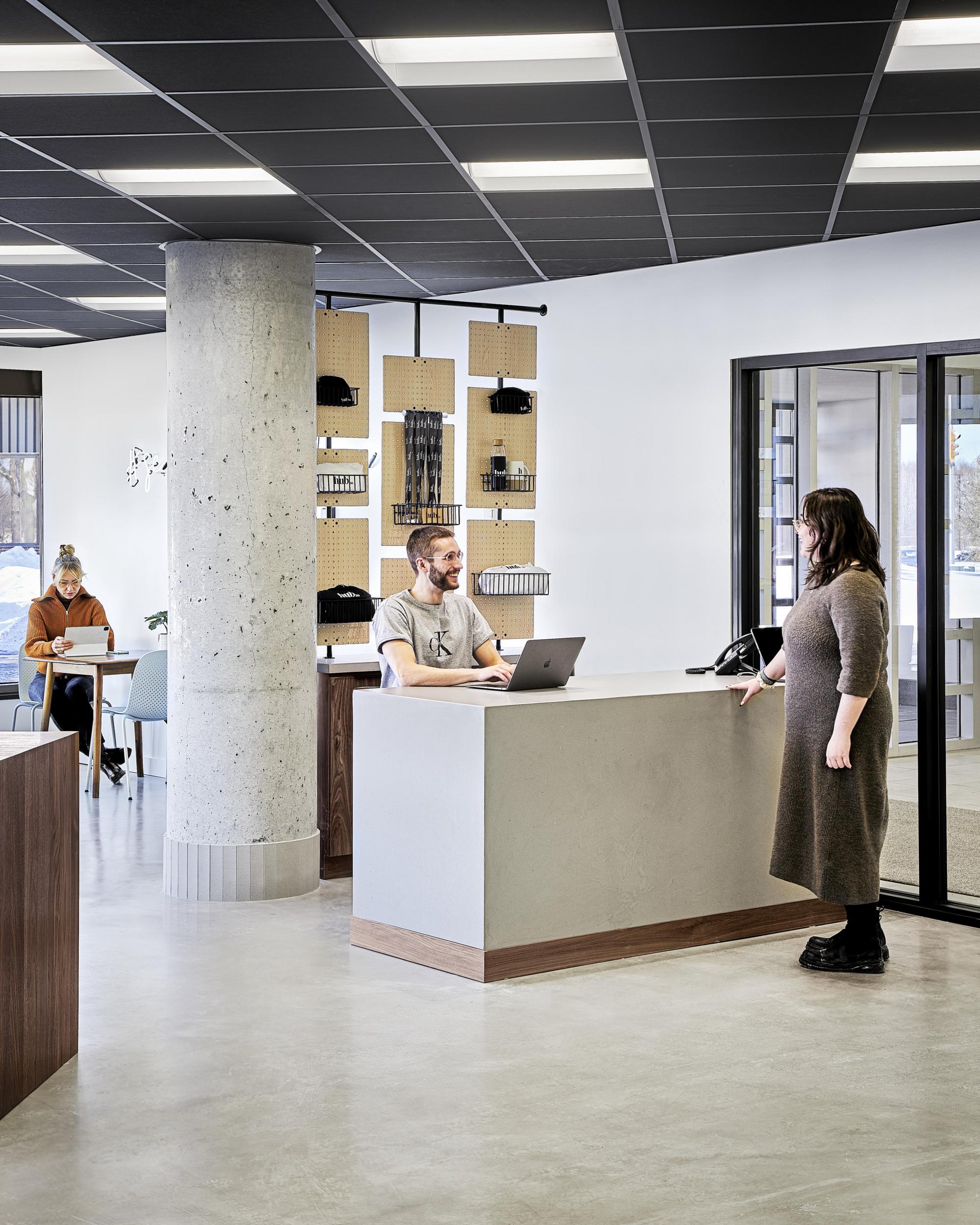 Smiling person having a conversation with another person around a table within Hub350 business center with another person working at another table in the background. 