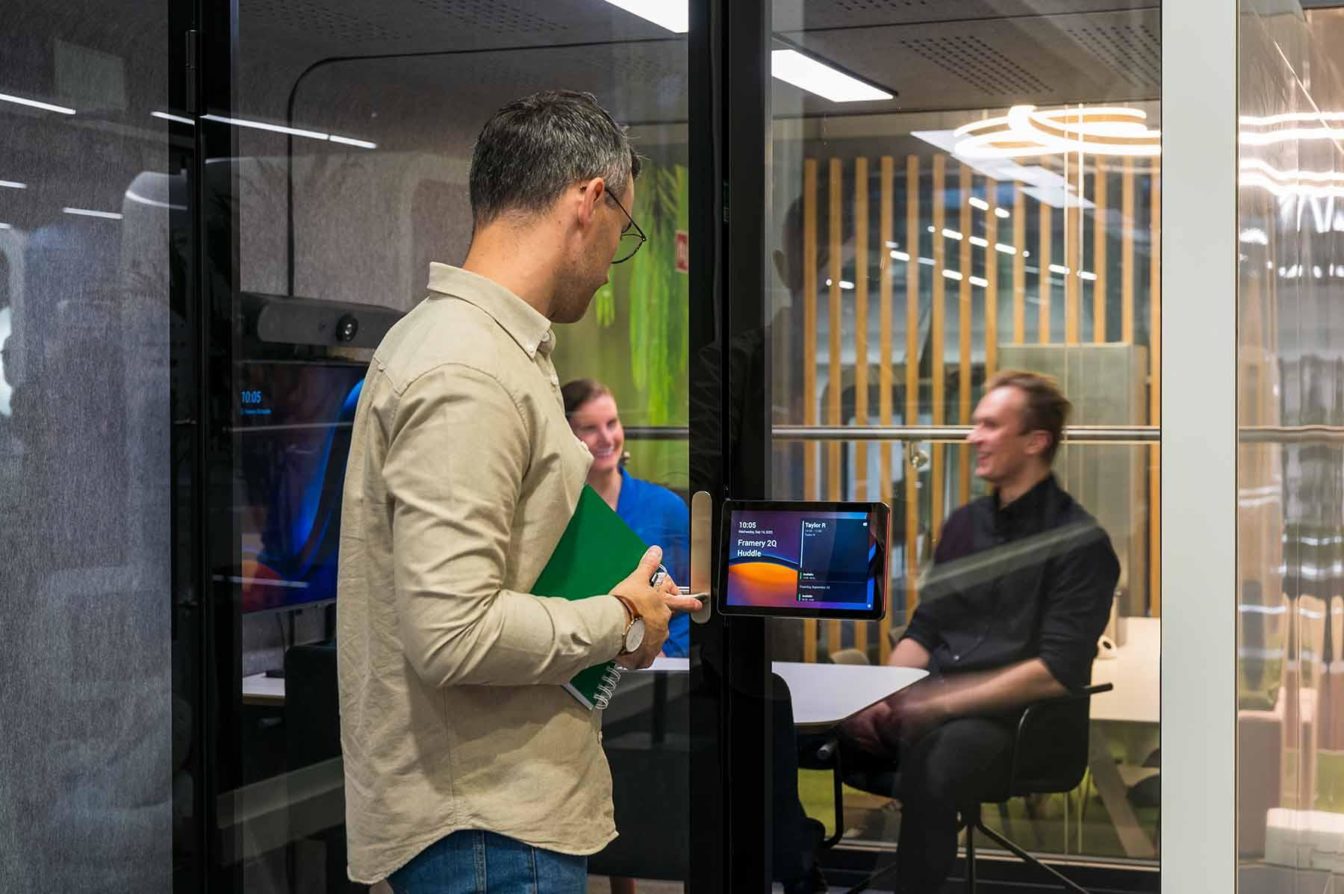 Person entering a Framery pod for a hybrid meeting with co-workers.