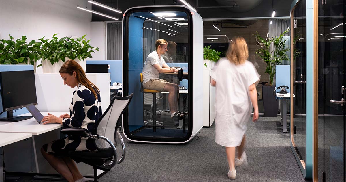 Man working in a white Framery One office pod in an open plan office