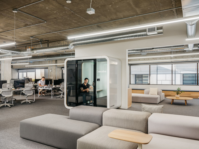 Man working inside a Framery Q in an open plan office.