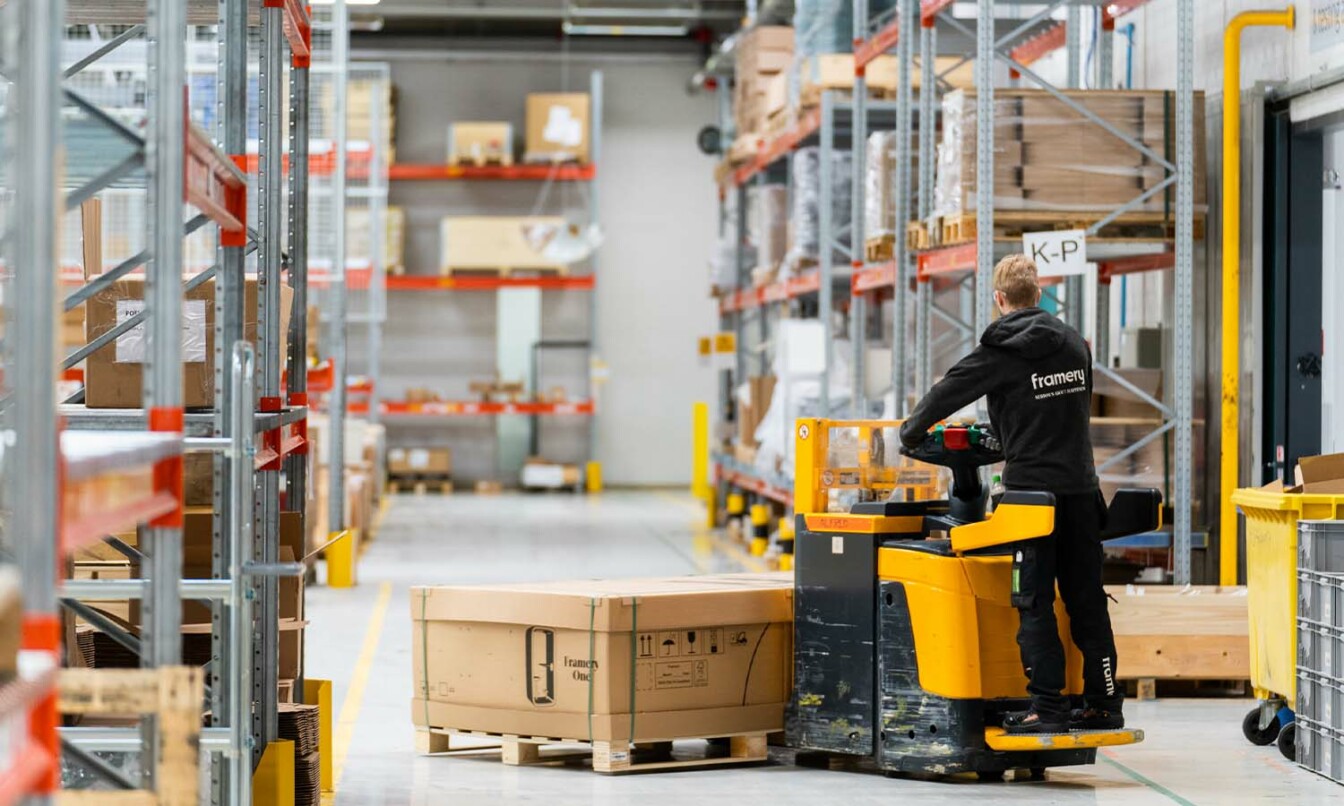 A factory worker moving a packaged Framery pod made in Finland, with a truck.