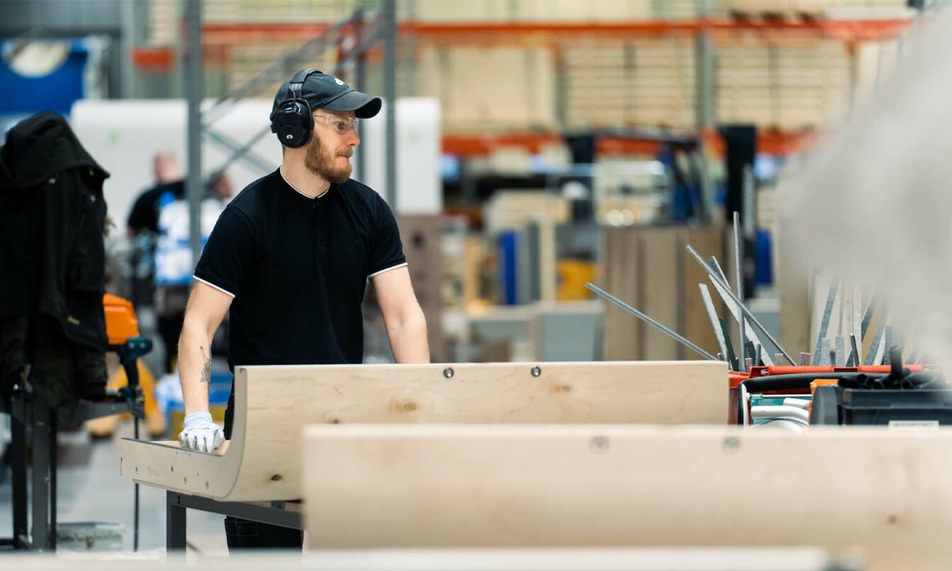 Framery production worker handling a wooden frame of a Framery pod.