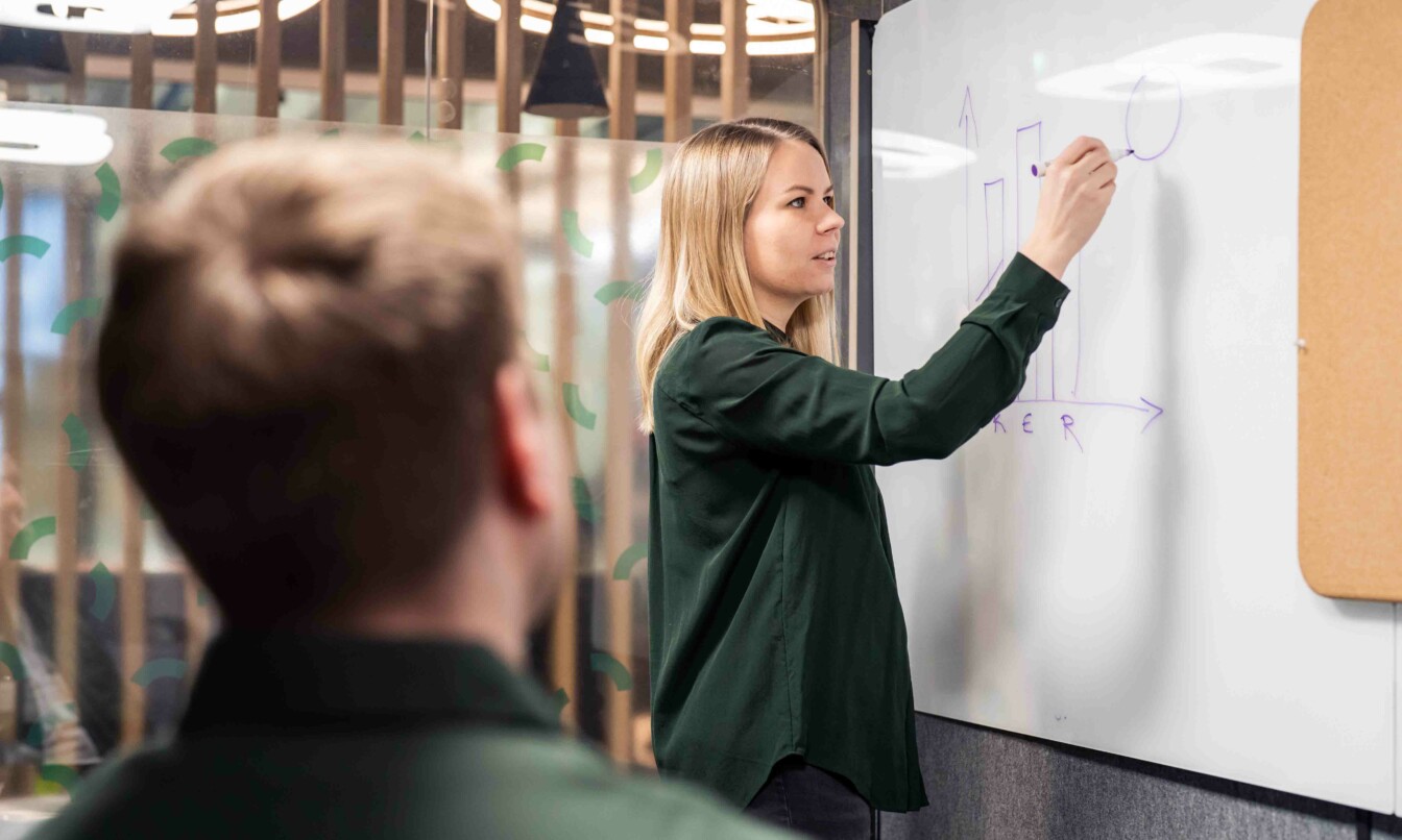 Framery worker demonstrating their point by writing on a whiteboard in a Framery 2Q meeting room.