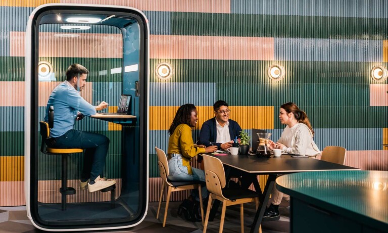 Person working in a Framery One office pod that has an occupancy sensor within which automatically turns on the lights when one enters the pod.