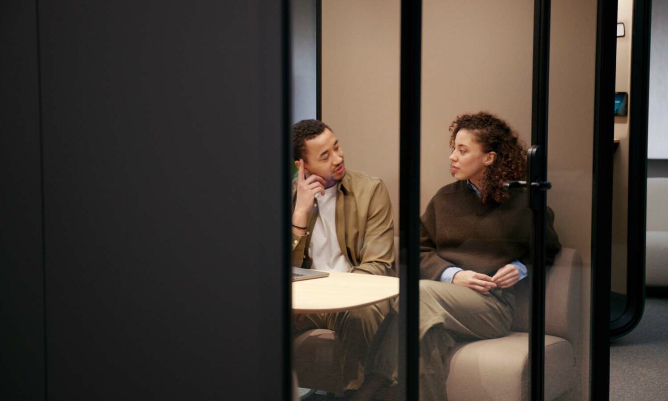 People having a conversation in a Framery Four soundproof study space.