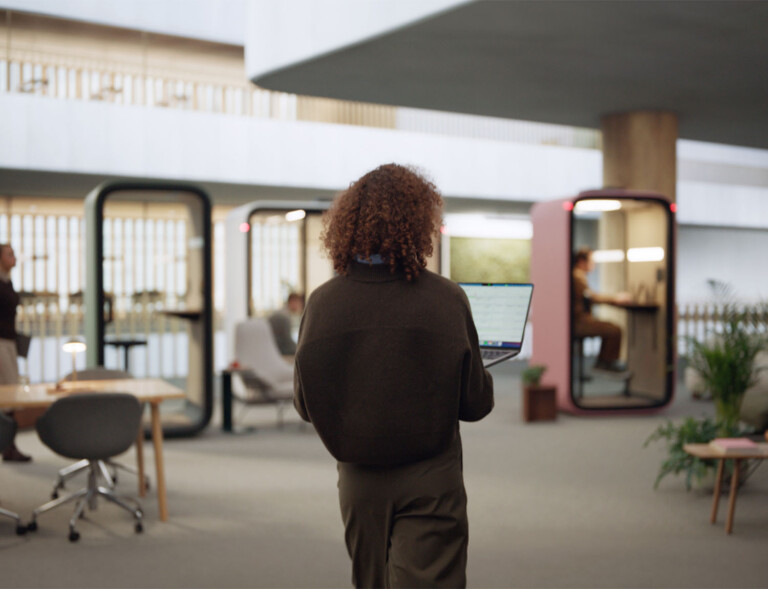 A person walking towards a Framery smart pod.