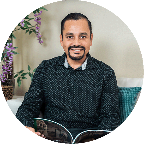 Smiling person sitting on a sofa with a magazine.