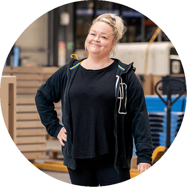 Smiling person standing in front of a production floor.