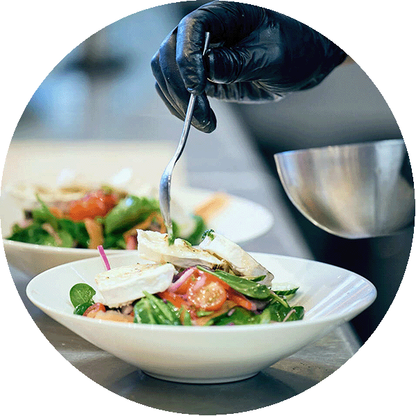 Salat on a plate and a hand adding dressing on it.