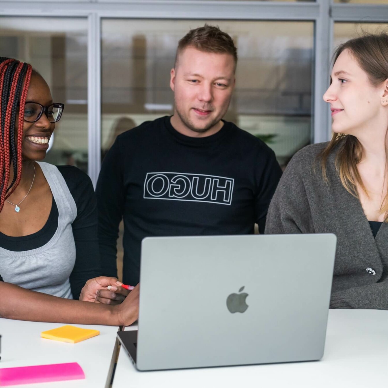 Three people working in front of a laptop.