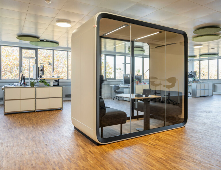 A beige office pod in an office with wooden floor.