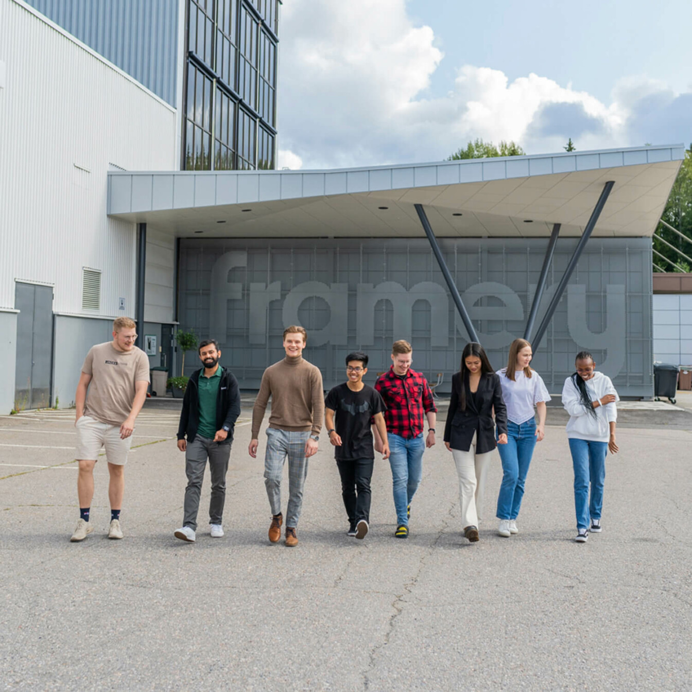 A group of young people walking in a row with an office building behind them.