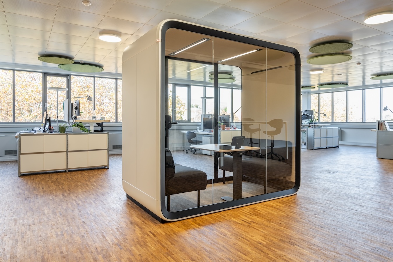 A beige office pod in an office with wooden floor.