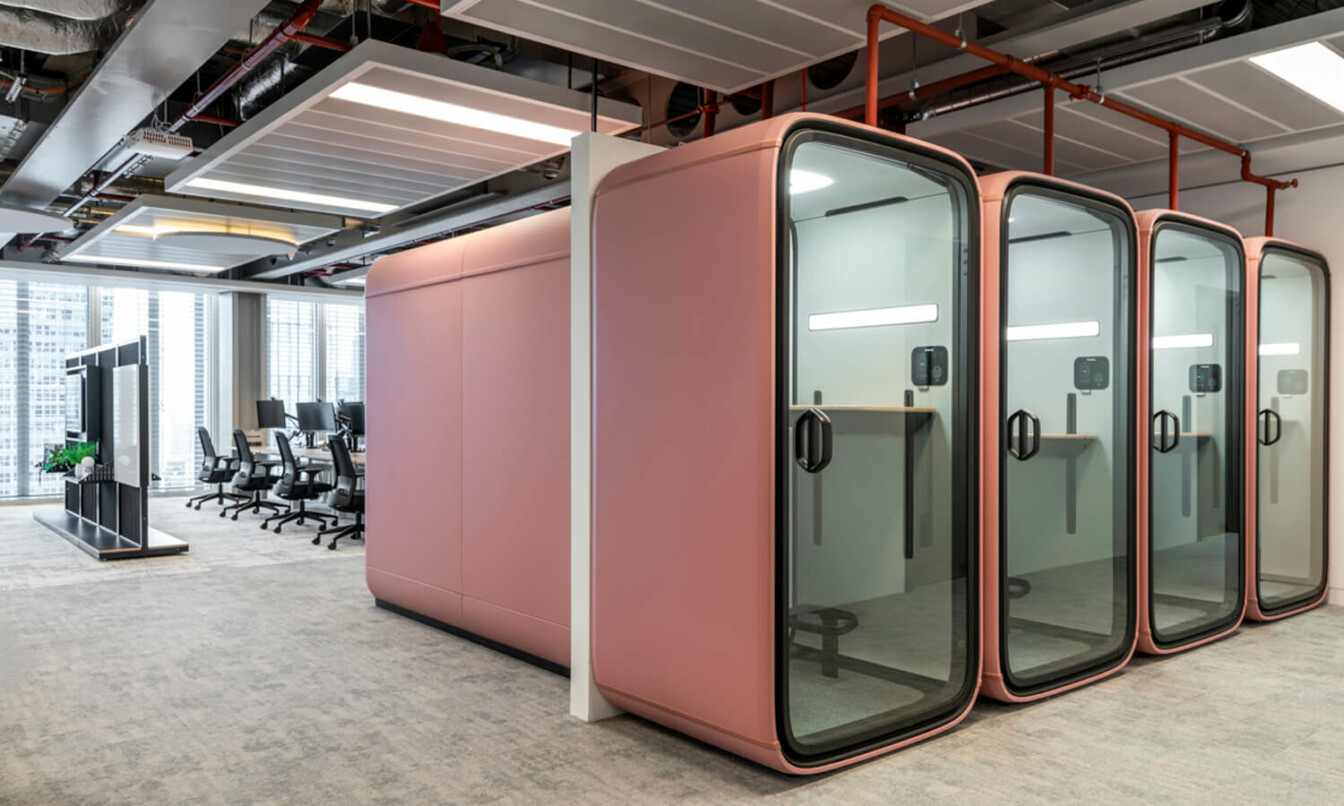 A fleet of blush colored Framery pods in an office setting.