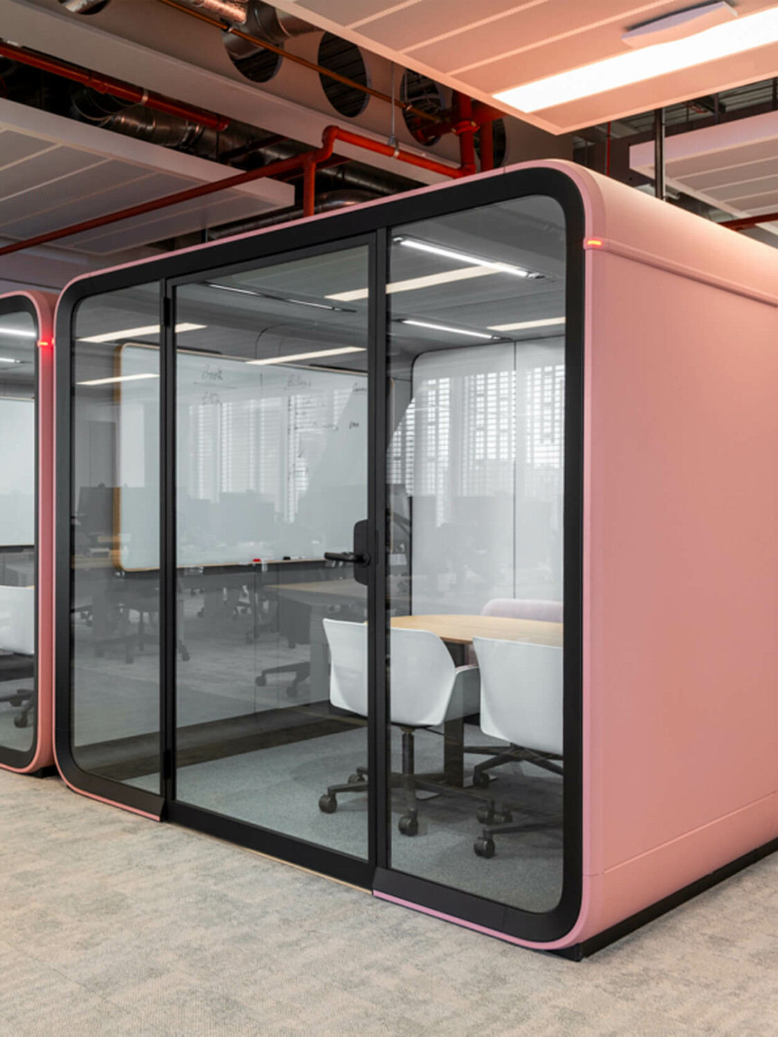 A blush colored Framery Six meeting pod in an office.