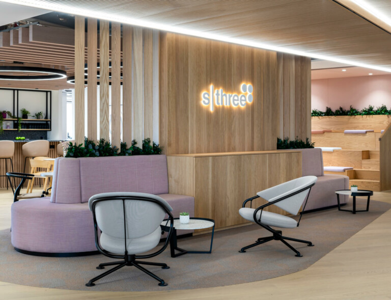 An office lobby with pastel color seating and light wood wall structure as background.