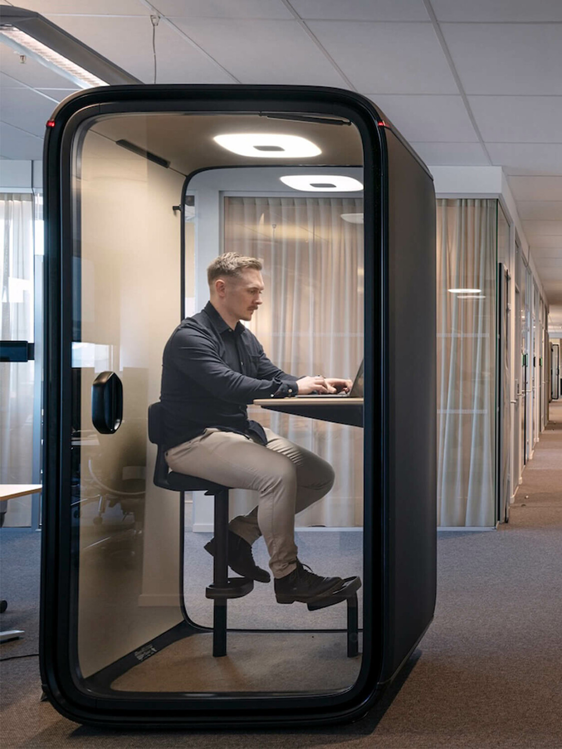 Man sitting inside a blue Framery pod in an office.