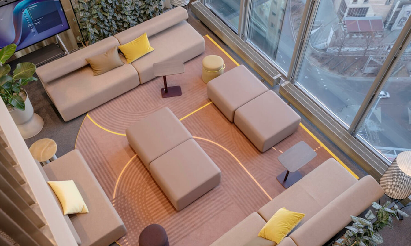 A powder colored sofa setting in an office from a bird perspective.