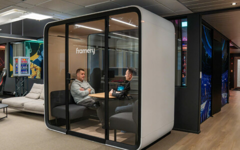 Two men sitting inside a white Framery pod inside an office.