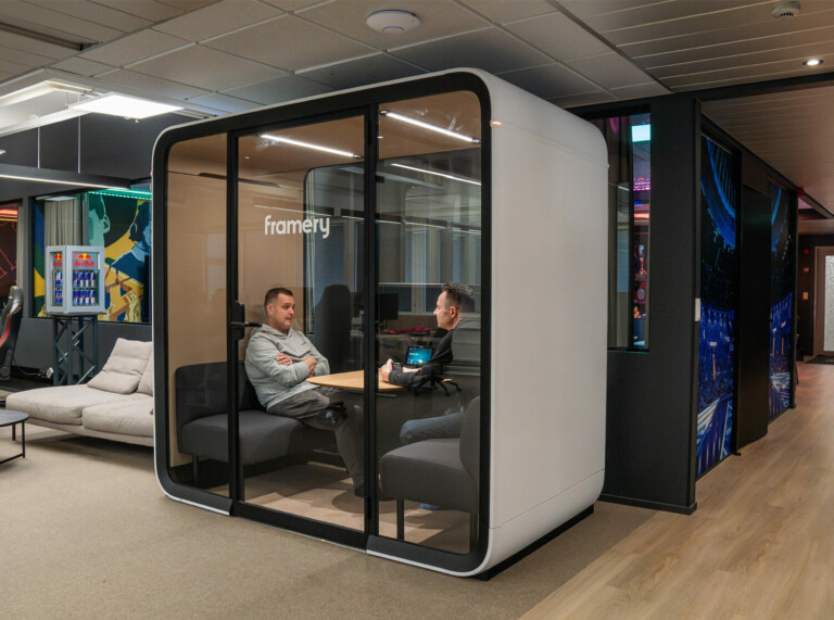 Two men sitting inside a white Framery pod inside an office.