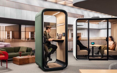 A person working inside a Framery One Compact office phone booth.