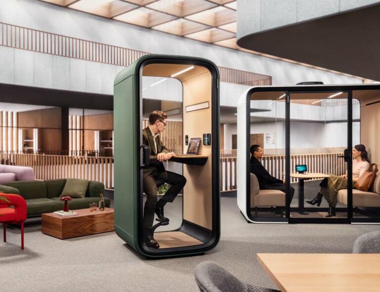 A person working inside a Framery One Compact office phone booth.