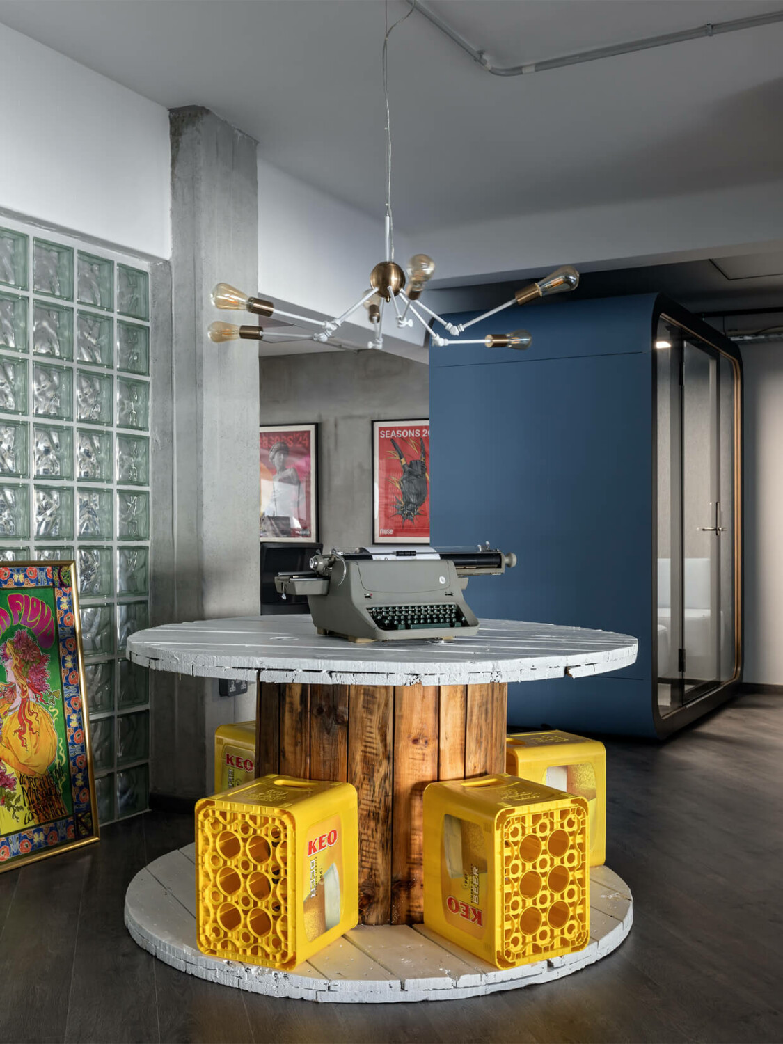 A DIY table and chairs in an office and a blue Framery pod in the background.