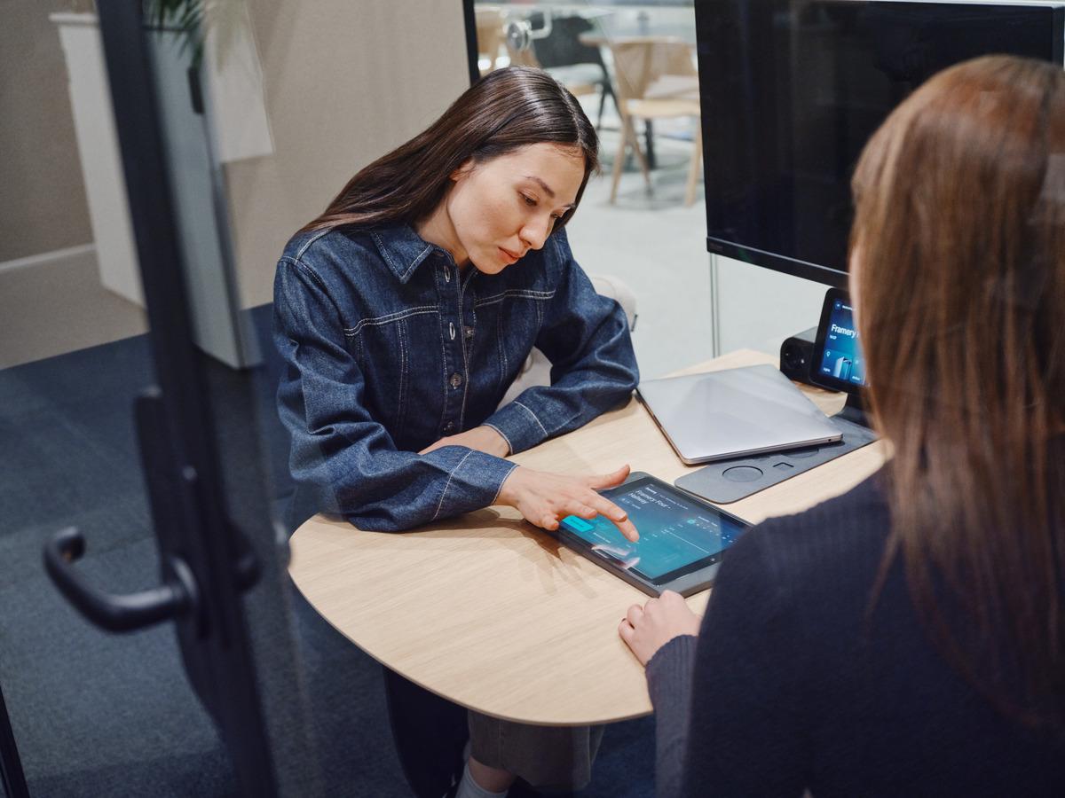 A woman working on a tablet on top of a table.