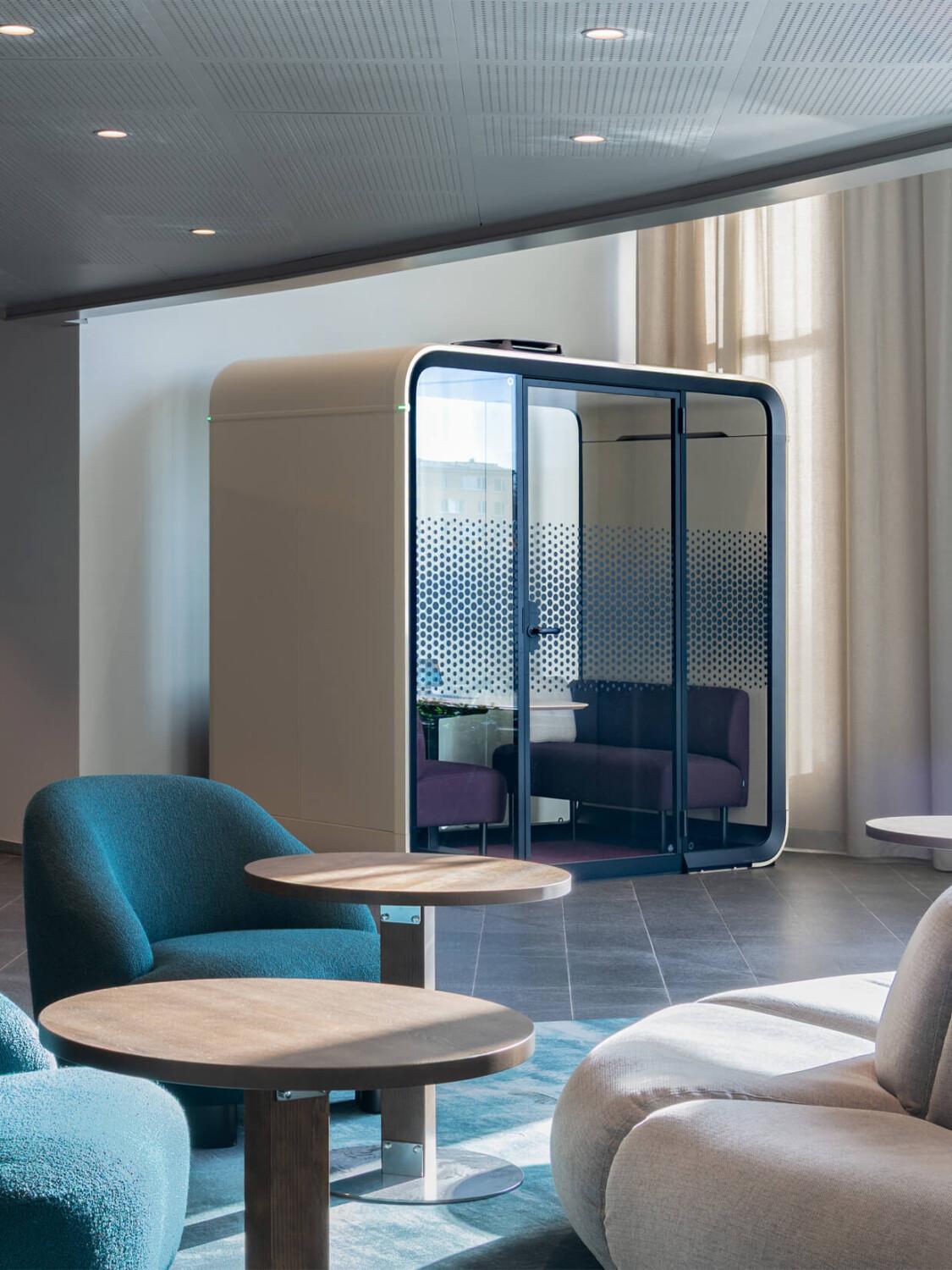 A sand colored office pod in the corner of a stylish office lobby.