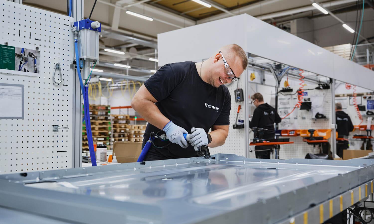 Happy looking man drilling aluminium in a factory setting.