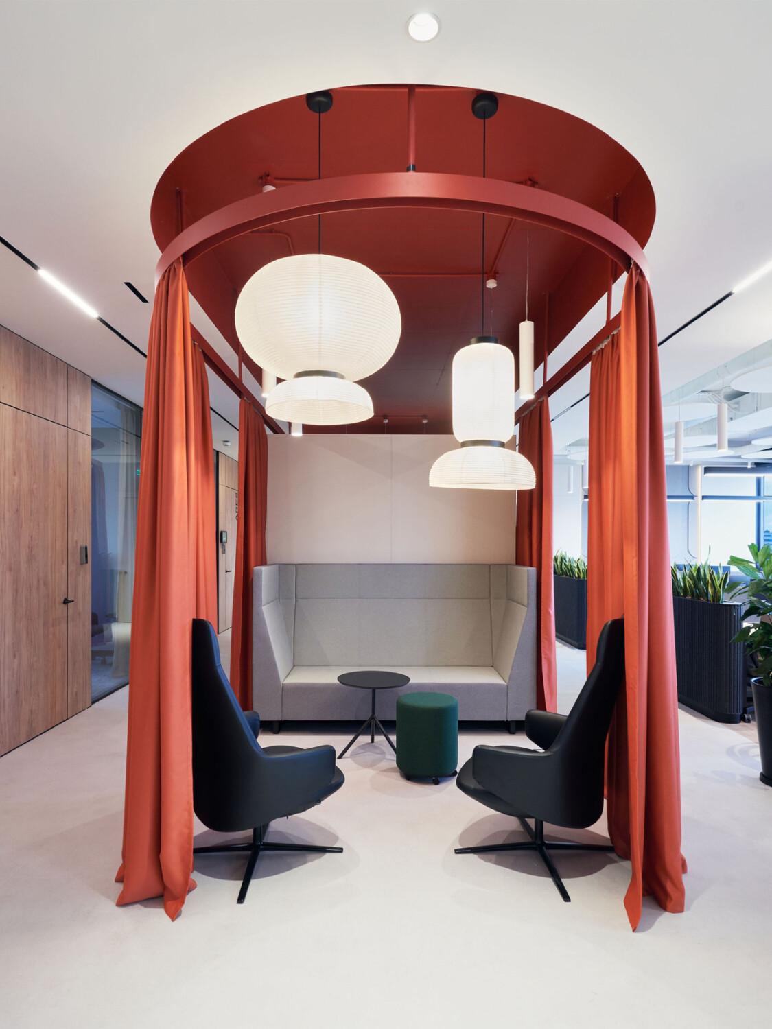 A stylish office lounge with red curtains and big lights.