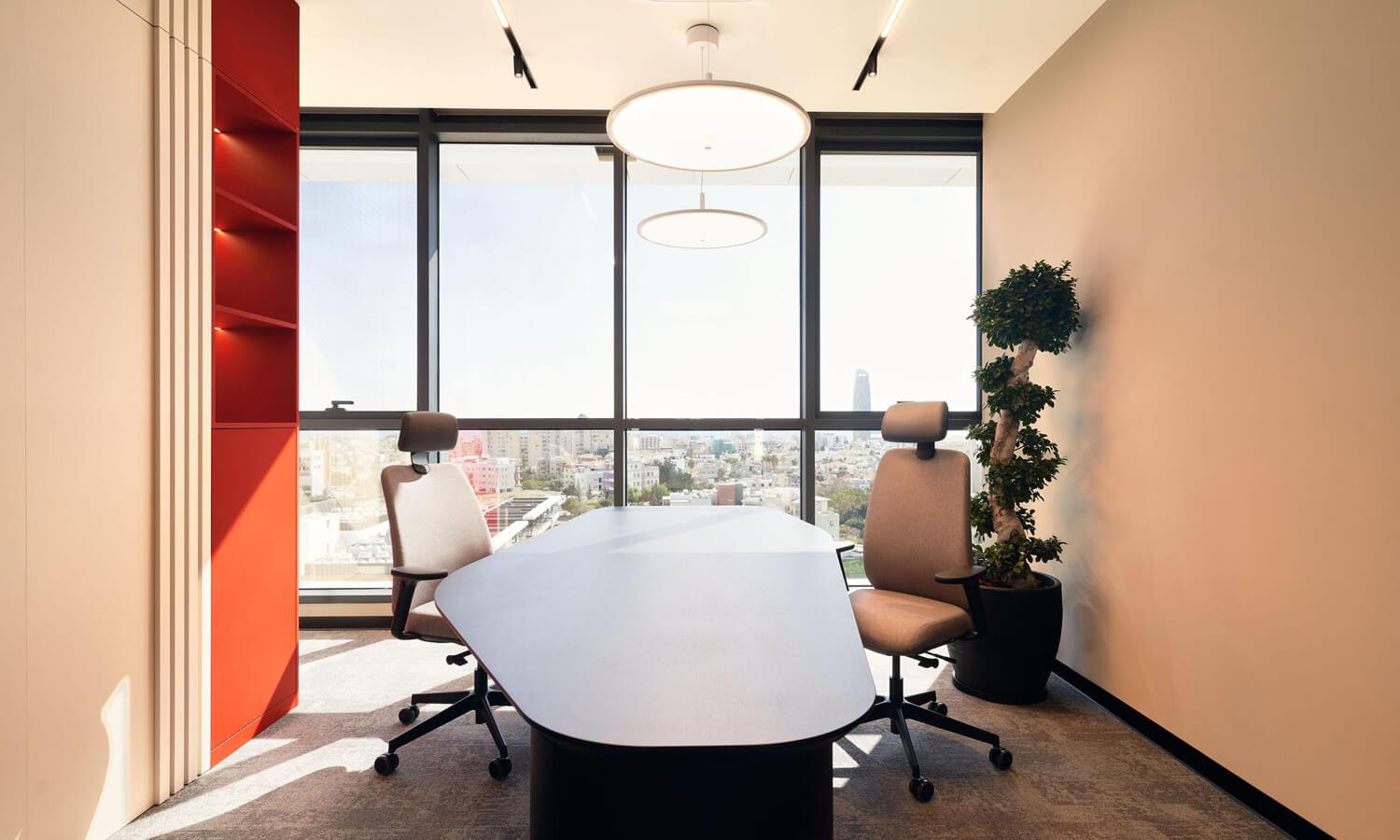 Meeting room with a big window and two chairs facing the camera.