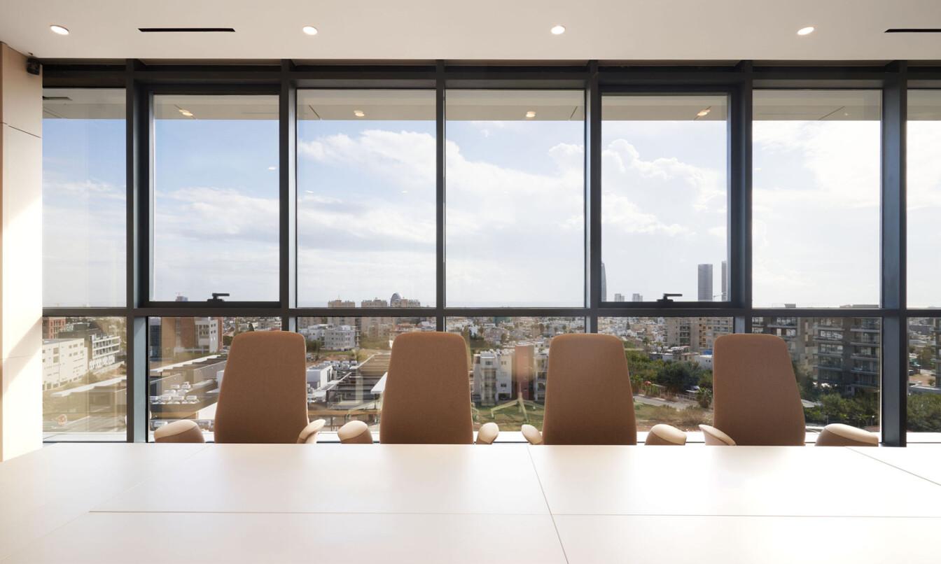 A row of office chairs facing a window with a nice view.