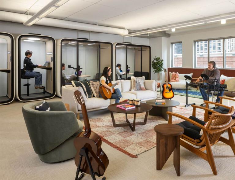 A lively office scene with Framery smart pods in the background and lounge area in the front.
