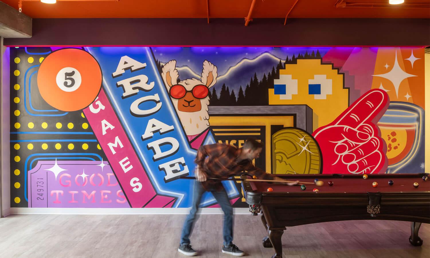 A colorful office wall mural with a pool table in front of the wall.