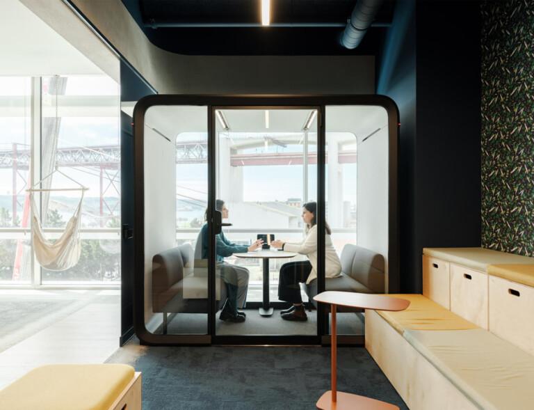 Office pod in front of a window with 2 persons inside
