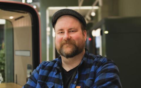 Facial image of a bearded man with a cap and a plaid shirt.
