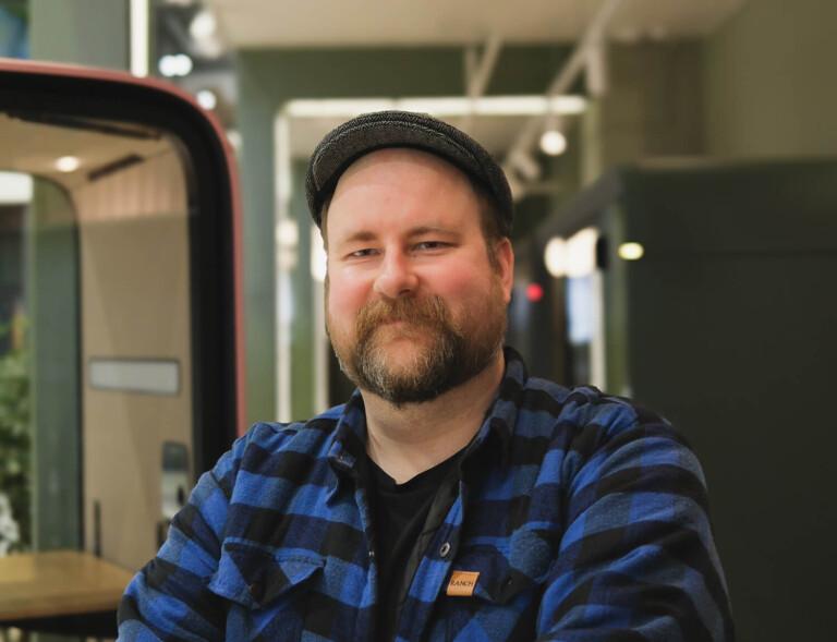 Facial image of a bearded man with a cap and a plaid shirt.