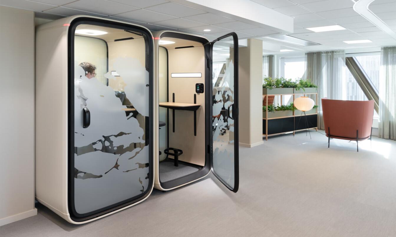 Two Framery One office pods in an office, one pod with open door.