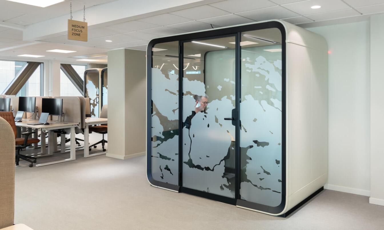 A sand colored Framery Four meeting pod in an office.