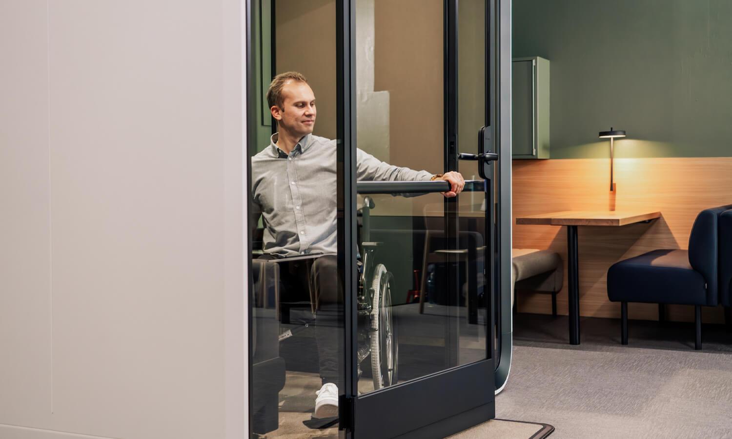 A man pulling the door close inside a wheelchair accessible pod.