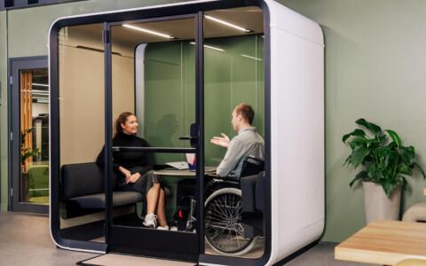 Two people, the other in a wheelchair, having a conversation in a wheelchair accessible meeting pod.