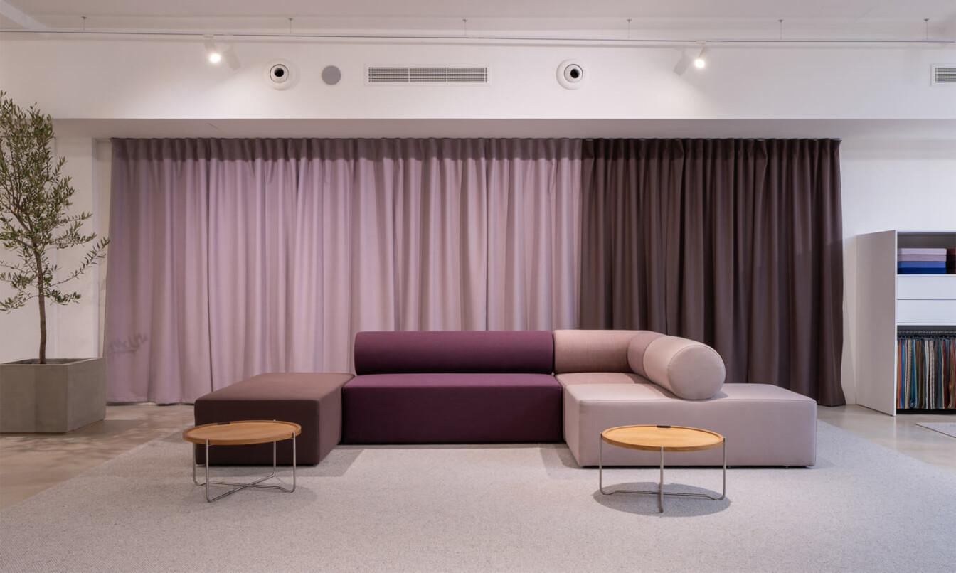 A purple and lavender colored sofa setting in a same colored surrounding curtains.