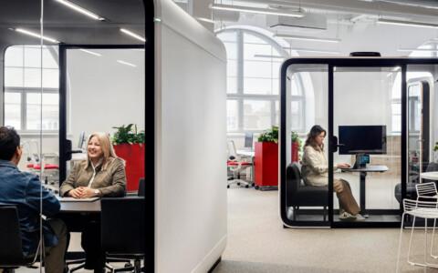 White Framery meeting pods in an office with people inside.