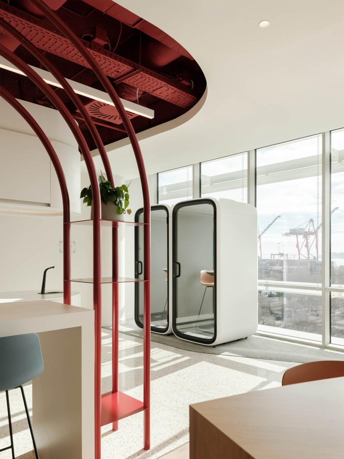 Two white Framery One office pods besides and office window.