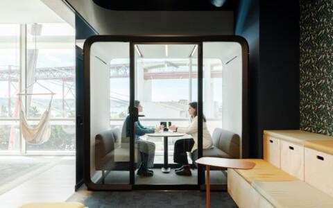 Two people sitting inside a Framery Four meeting pod at an office.