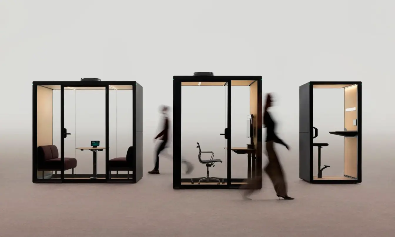 Three glass-walled Framery Gradus office pods with people walking past in a bright, minimalist space.