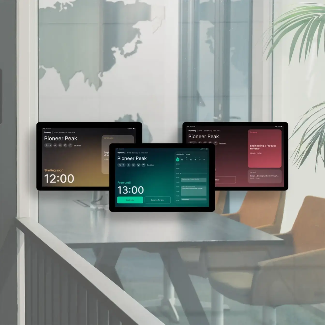 Several touchscreen displays showing dashboards sit on a conference table in a bright, modern meeting room.