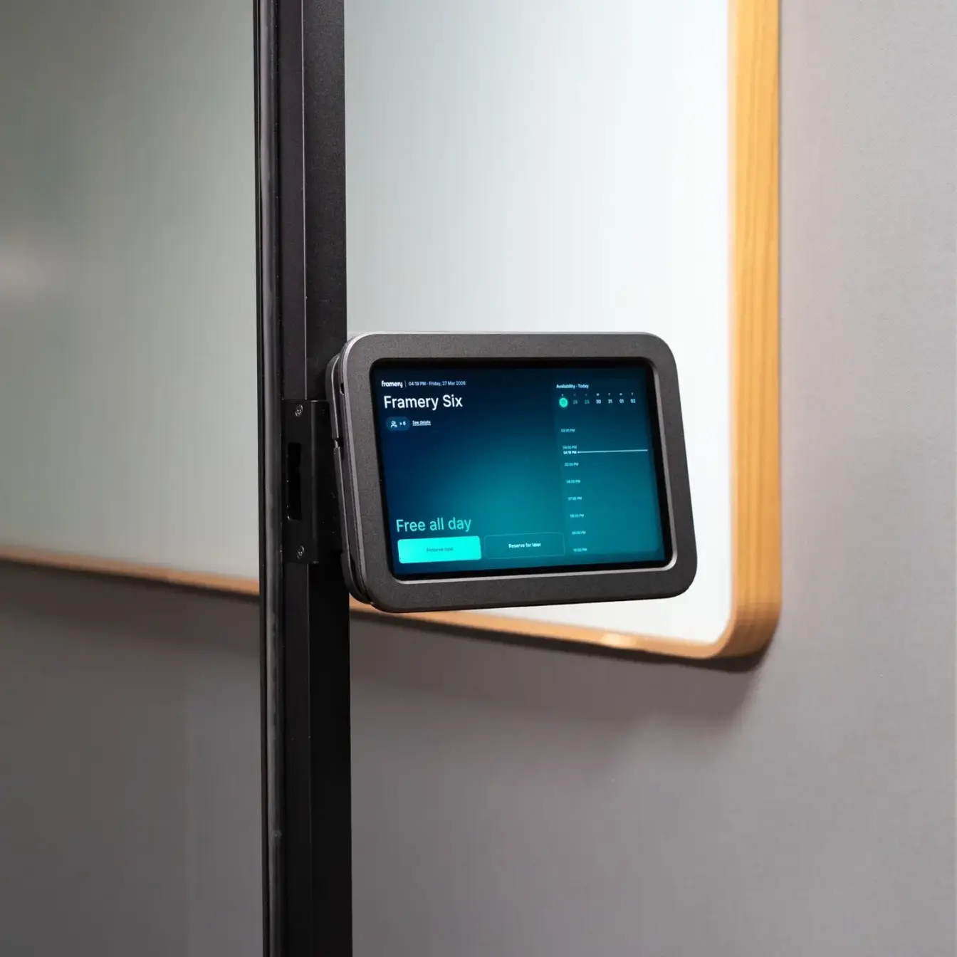 Small black touchscreen control panel mounted on a Framery Six door frame with a blue display.